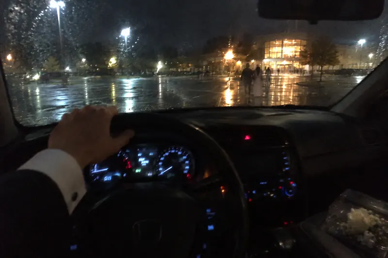View from a driver's seat across a rainy parking lot at night